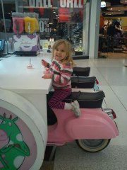 Chris White photo of daughter eating ice cream in the mall Four-year-old girl eating ice cream on a seat fashioned like a pink Vespa scooter